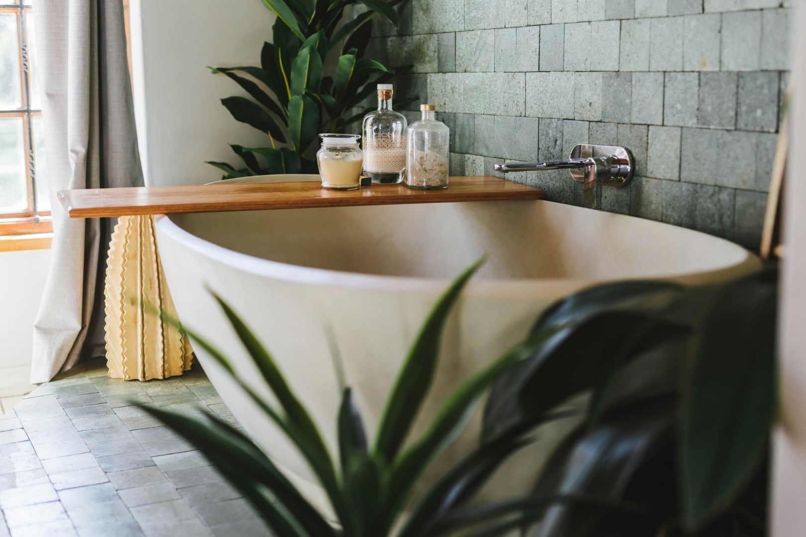 Freestanding bathtub beside a window with plants and tile backsplash after kitchen and bathroom remodeling in Avondale, AZ