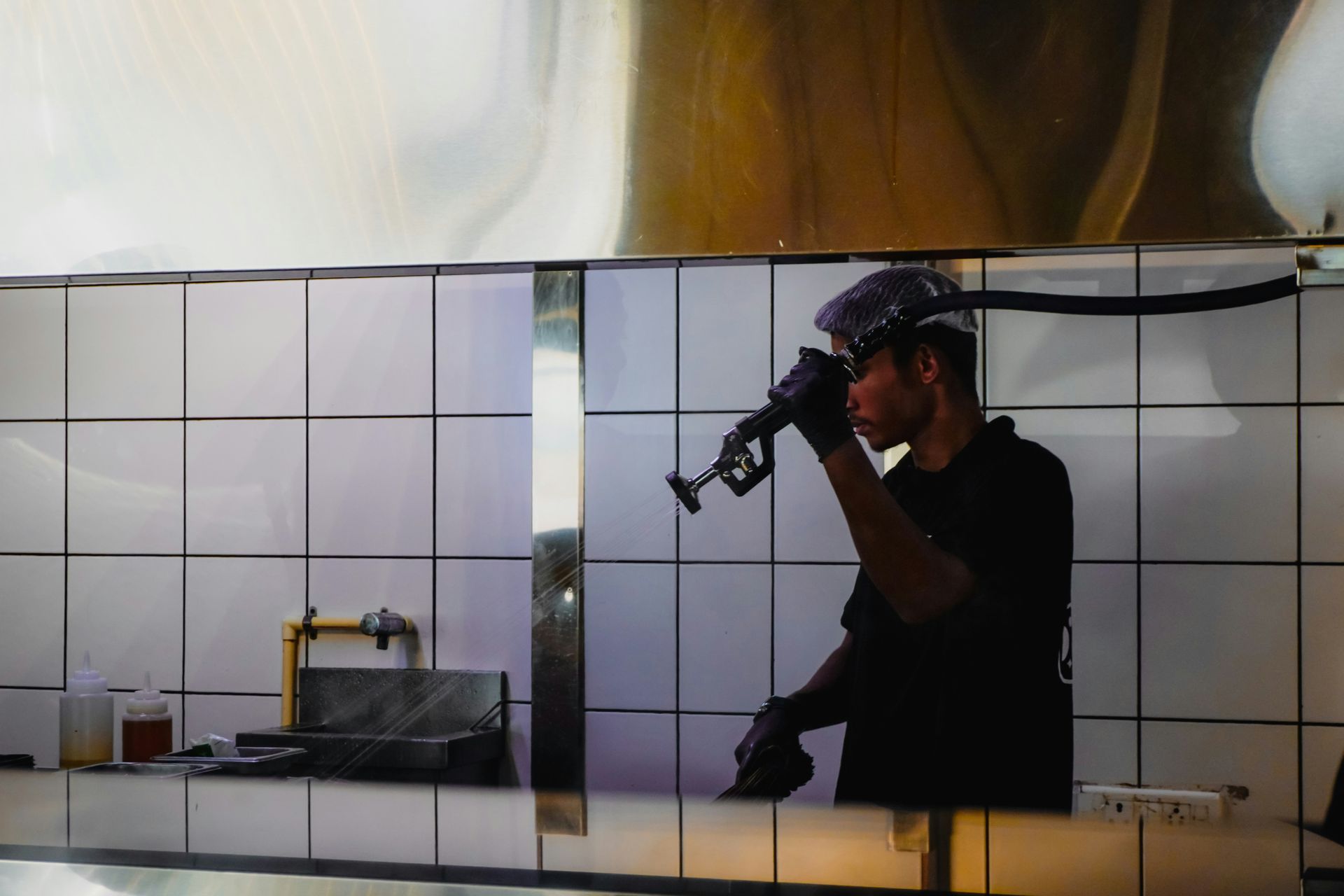 Worker installing kitchen backsplash tile behind a stove area during kitchen and bathroom remodeling in Avondale, AZ