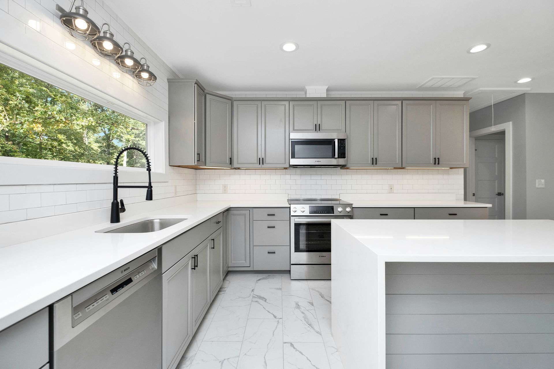 Modern white kitchen with gray cabinets, built-in appliances, and bright counters after bathroom remodeling in Avondale, AZ