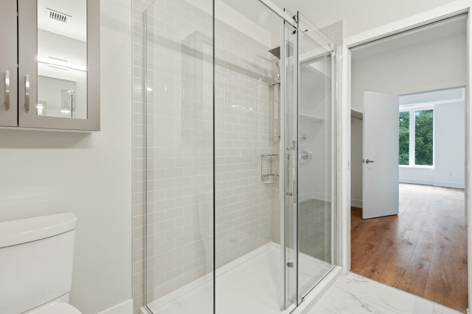 Clean glass shower with white tile walls and bright bathroom entry after kitchen and bathroom remodeling in Avondale, AZ