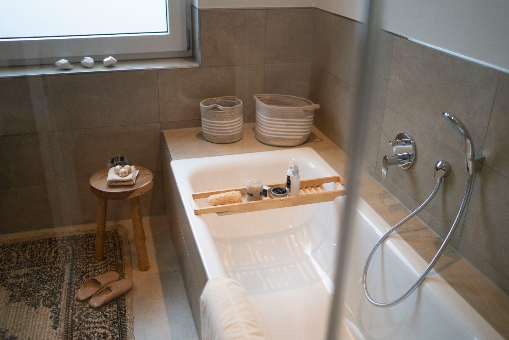 Bathtub with gray tile surround and handheld shower fixture after kitchen and bathroom remodeling in Avondale, AZ