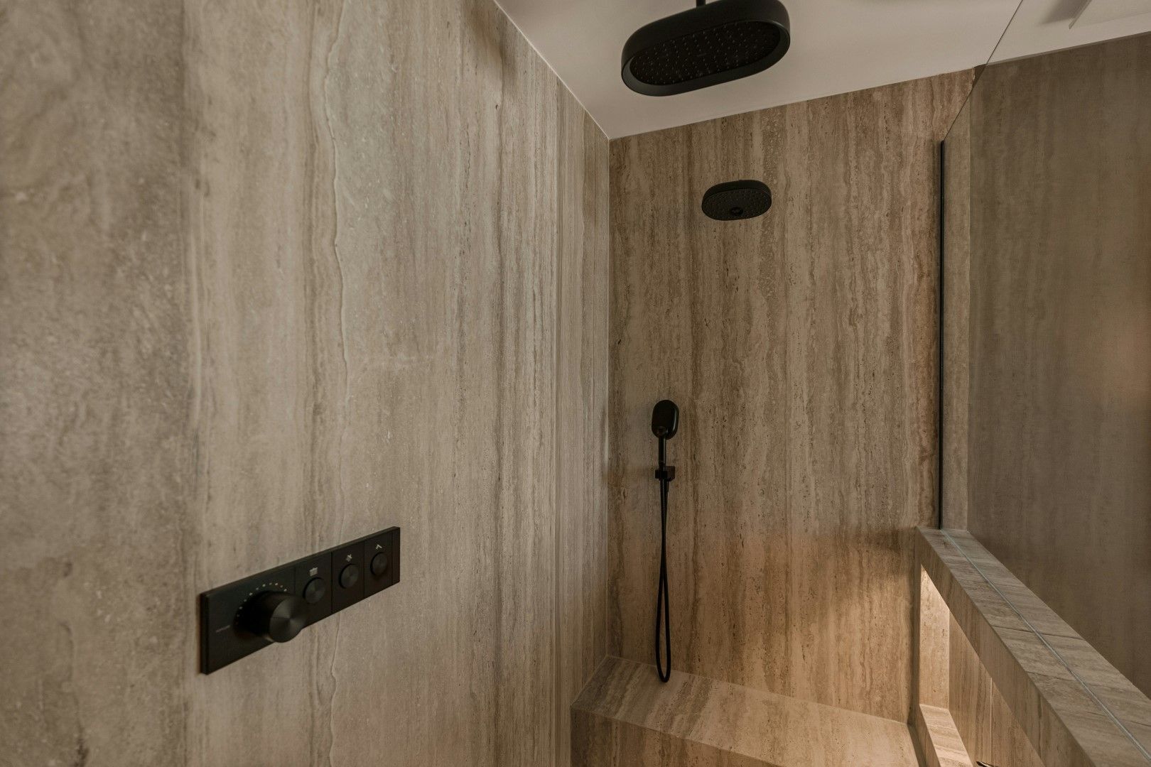 Close-up of a walk-in shower with textured tile walls and black fixtures during bathroom remodeling in Avondale, AZ