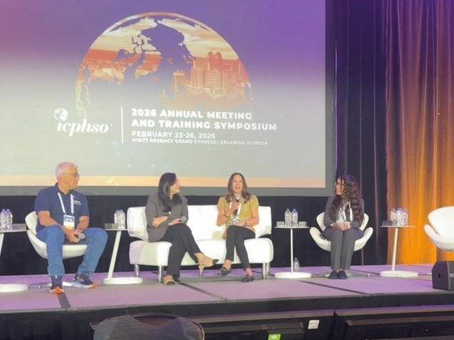 Panel discussion on a purple-lit stage with four speakers seated before a globe-themed presentation screen