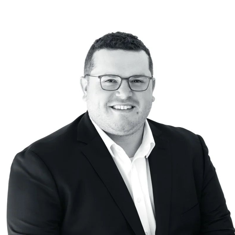 Smiling man in a black suit and glasses on a white background