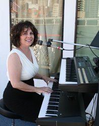 A woman is playing a keyboard in front of a window.