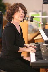 A woman is sitting at a piano with a microphone.