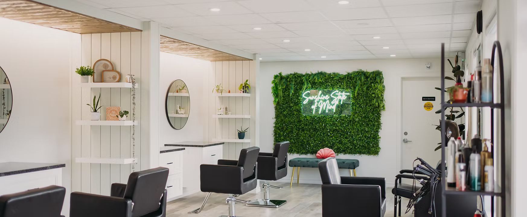 A hair salon with black chairs and a green wall.