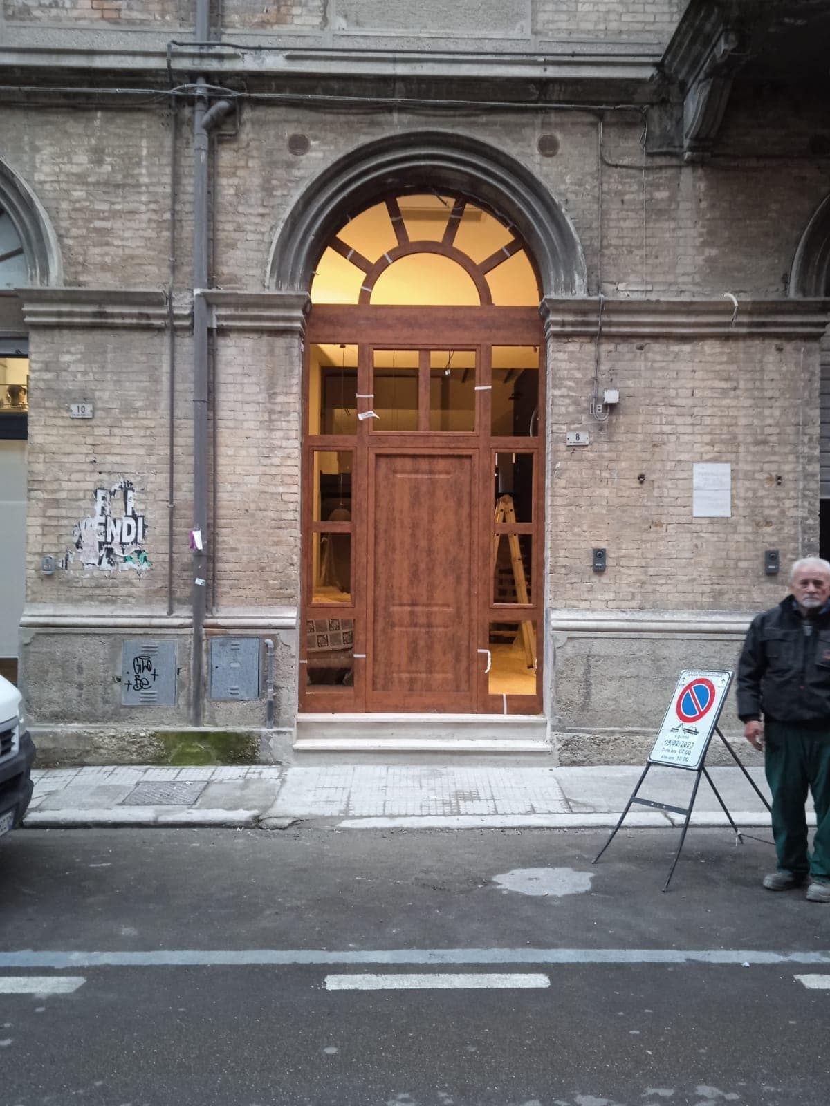 Un uomo in piedi davanti a un edificio con un cartello che dice