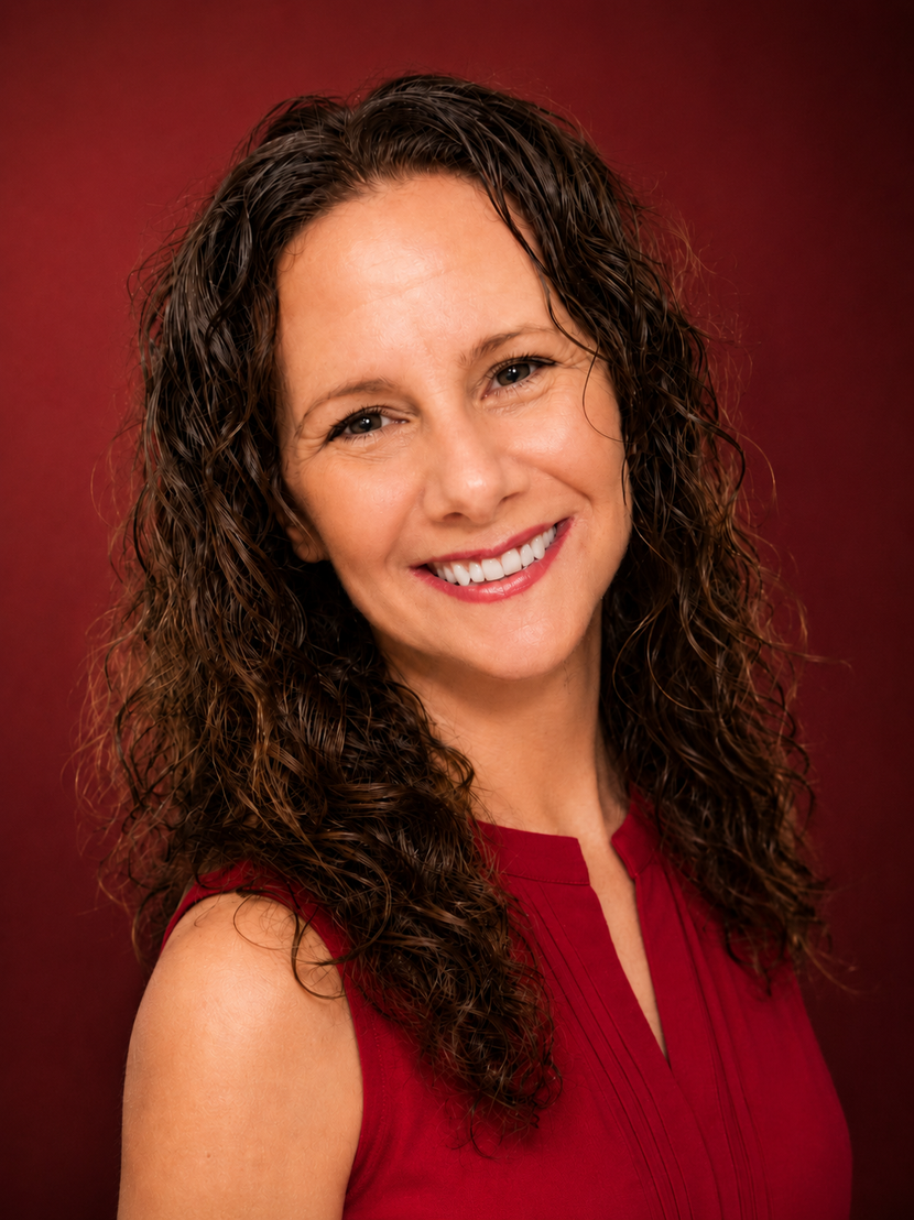 Woman with long curly hair smiles, wearing a red tank top that says 