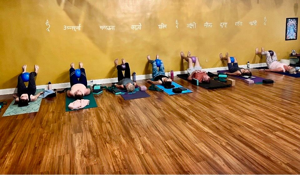 Adults practicing a wall-supported breathing and core exercise in class.