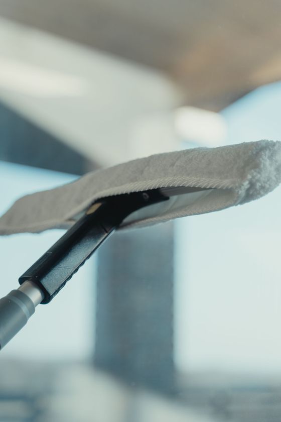 Worker cleaning a large window with a squeegee outside a building
