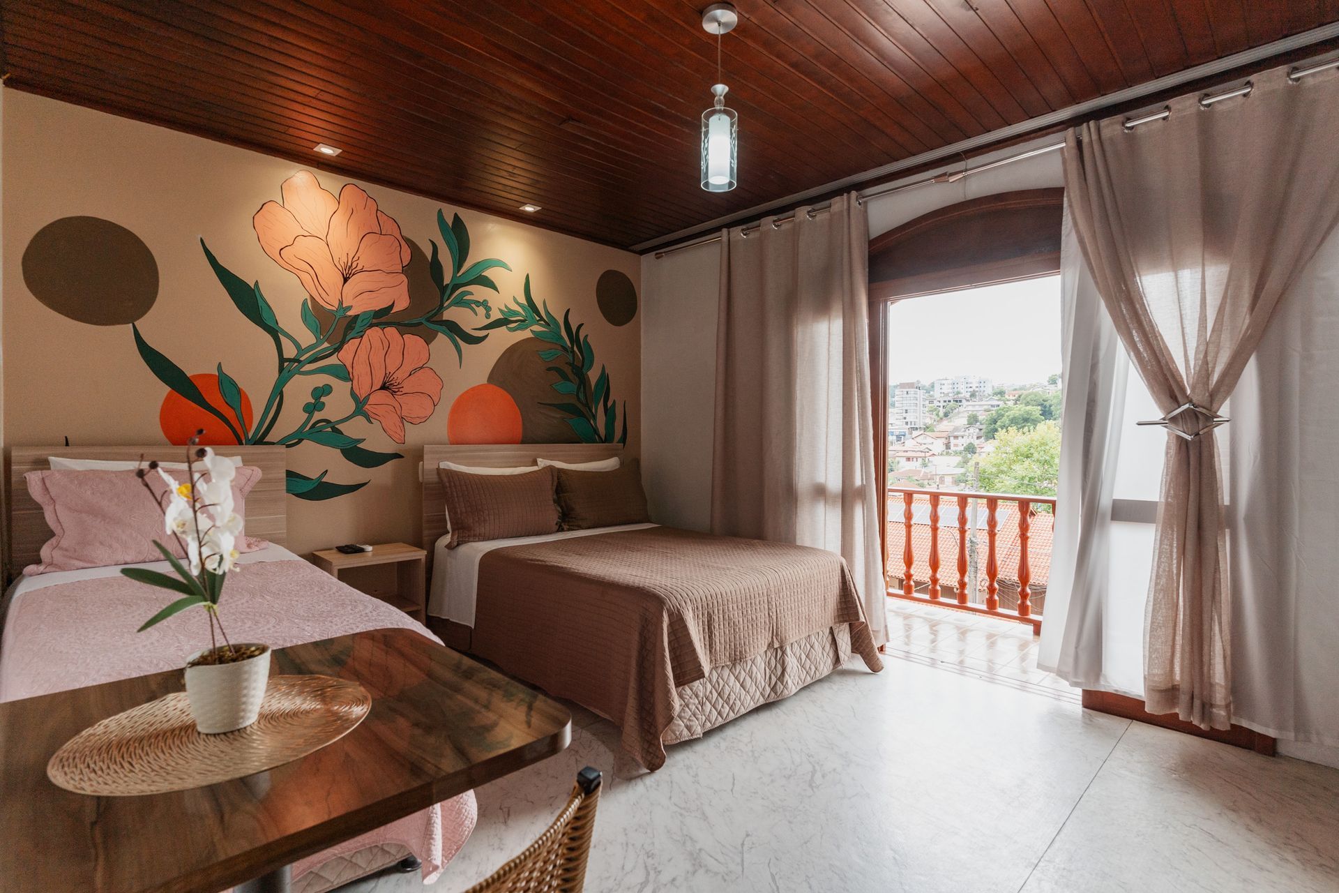 Um quarto de hotel com duas camas, uma mesa e uma varanda.- Pousada Santo Antônio