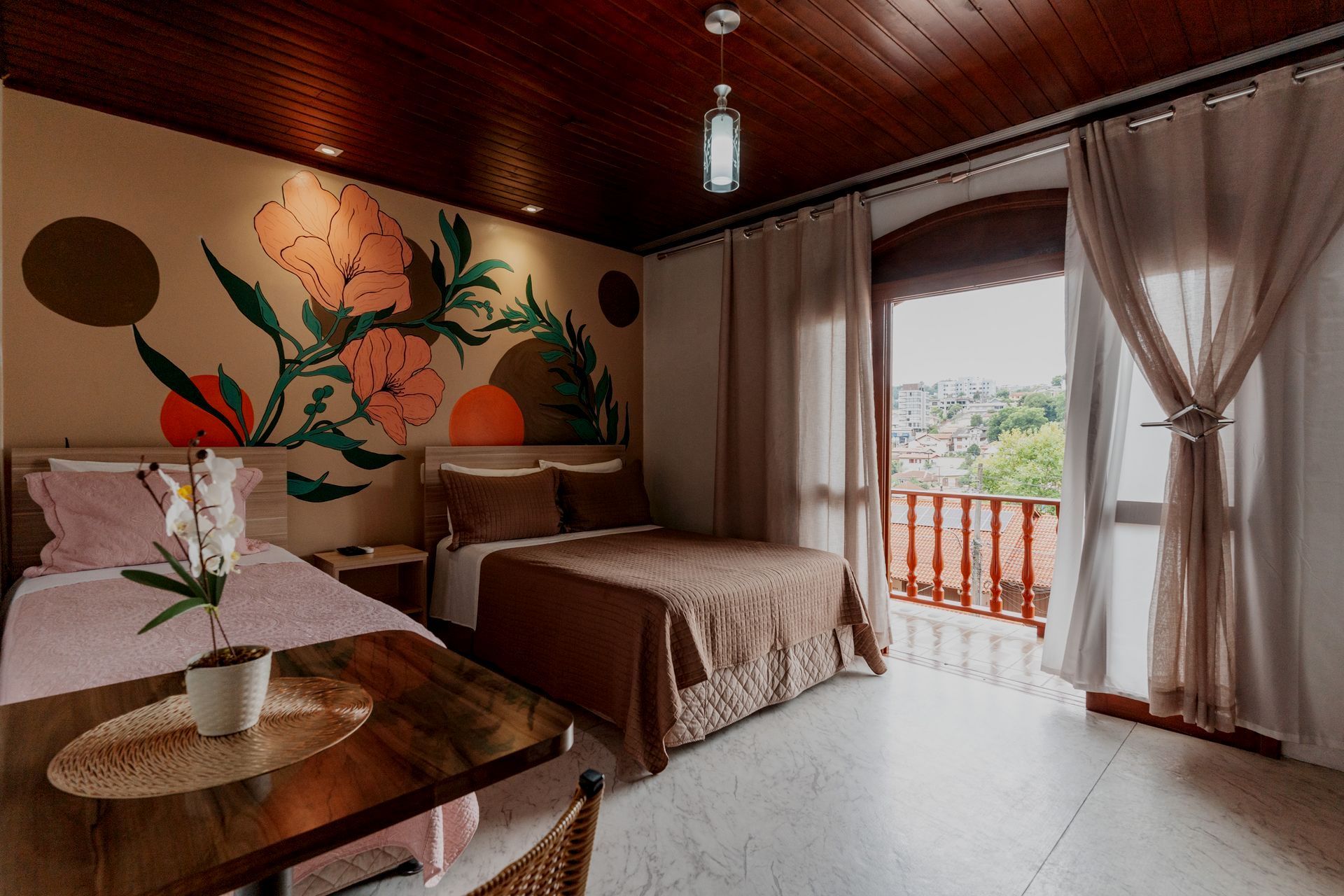 Um quarto de hotel com duas camas, uma mesa e uma varanda.- Pousada Santo Antônio