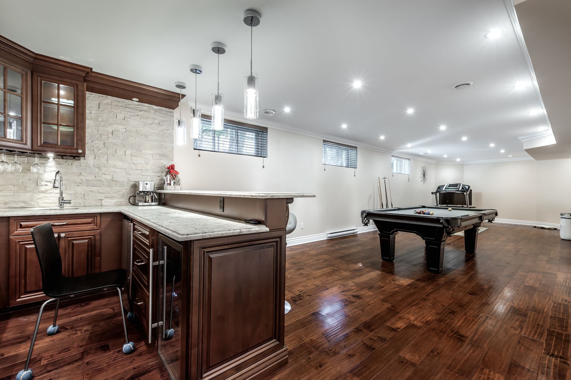 Basement with bar, pool table, and wood floors. Dark wood cabinets, neutral walls, and recessed lighting.