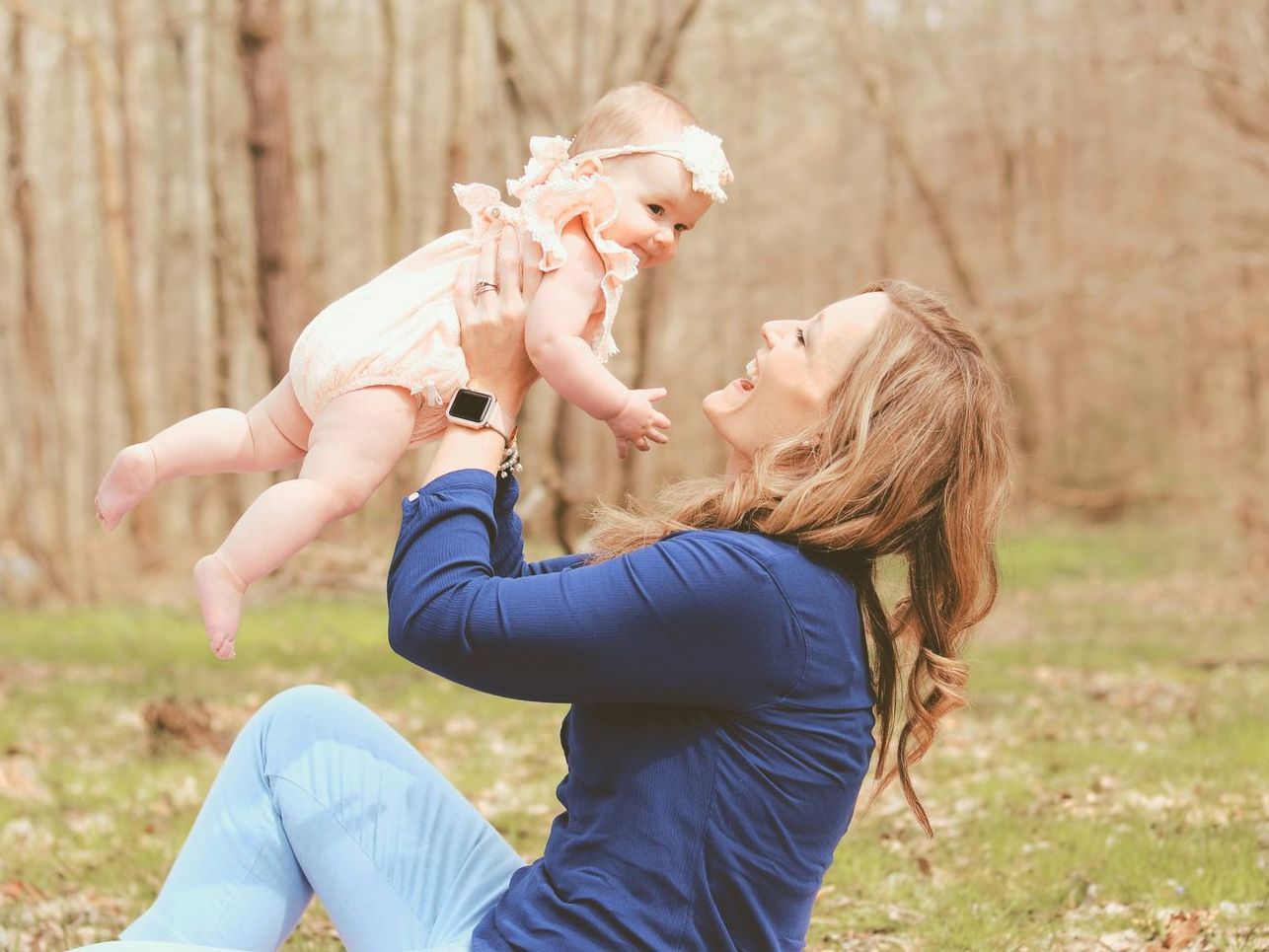 a woman is sitting on the ground holding a baby in the air .