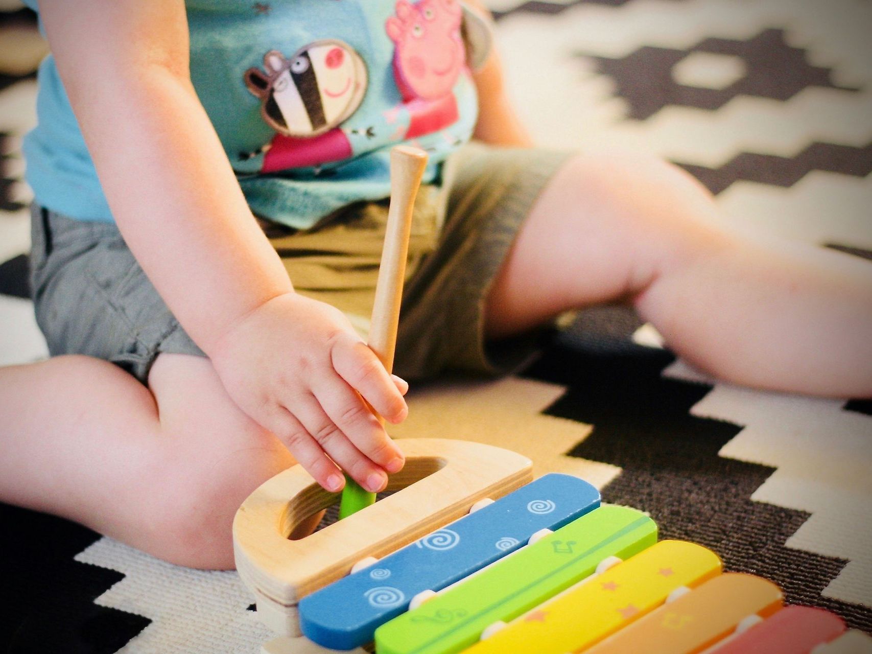 a baby is playing with a wooden xylophone on the floor .