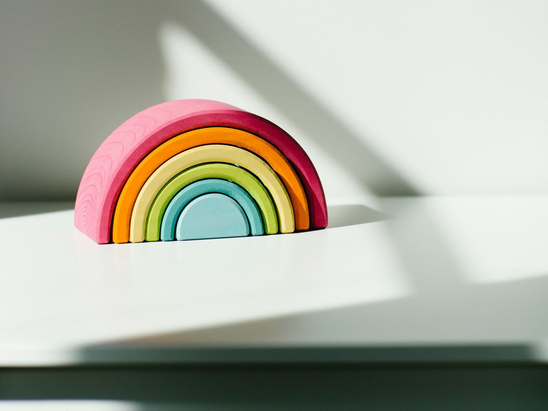 a small wooden rainbow is sitting on a white surface .