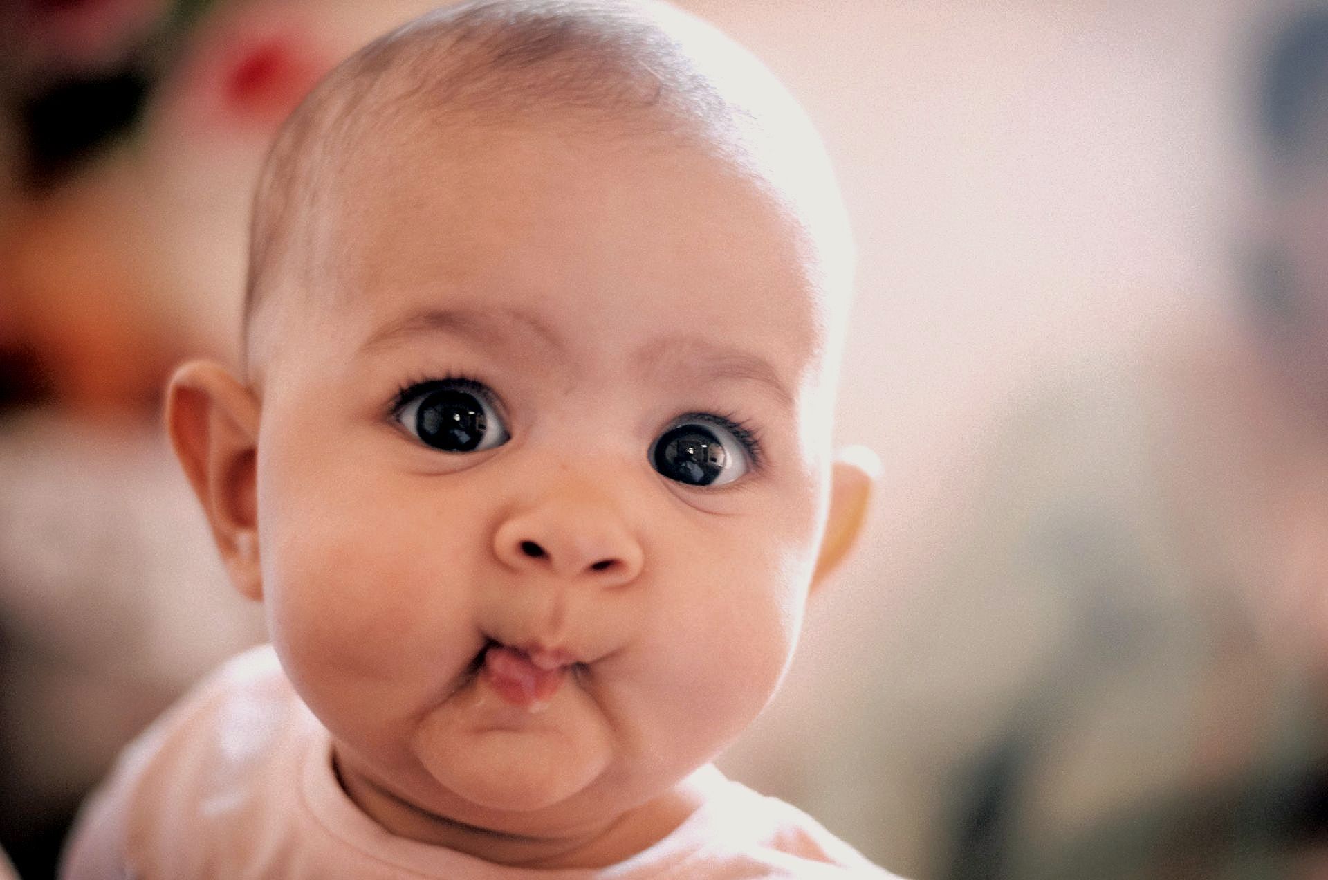 A close up photo of a baby with big brown eyes looking at the camera.