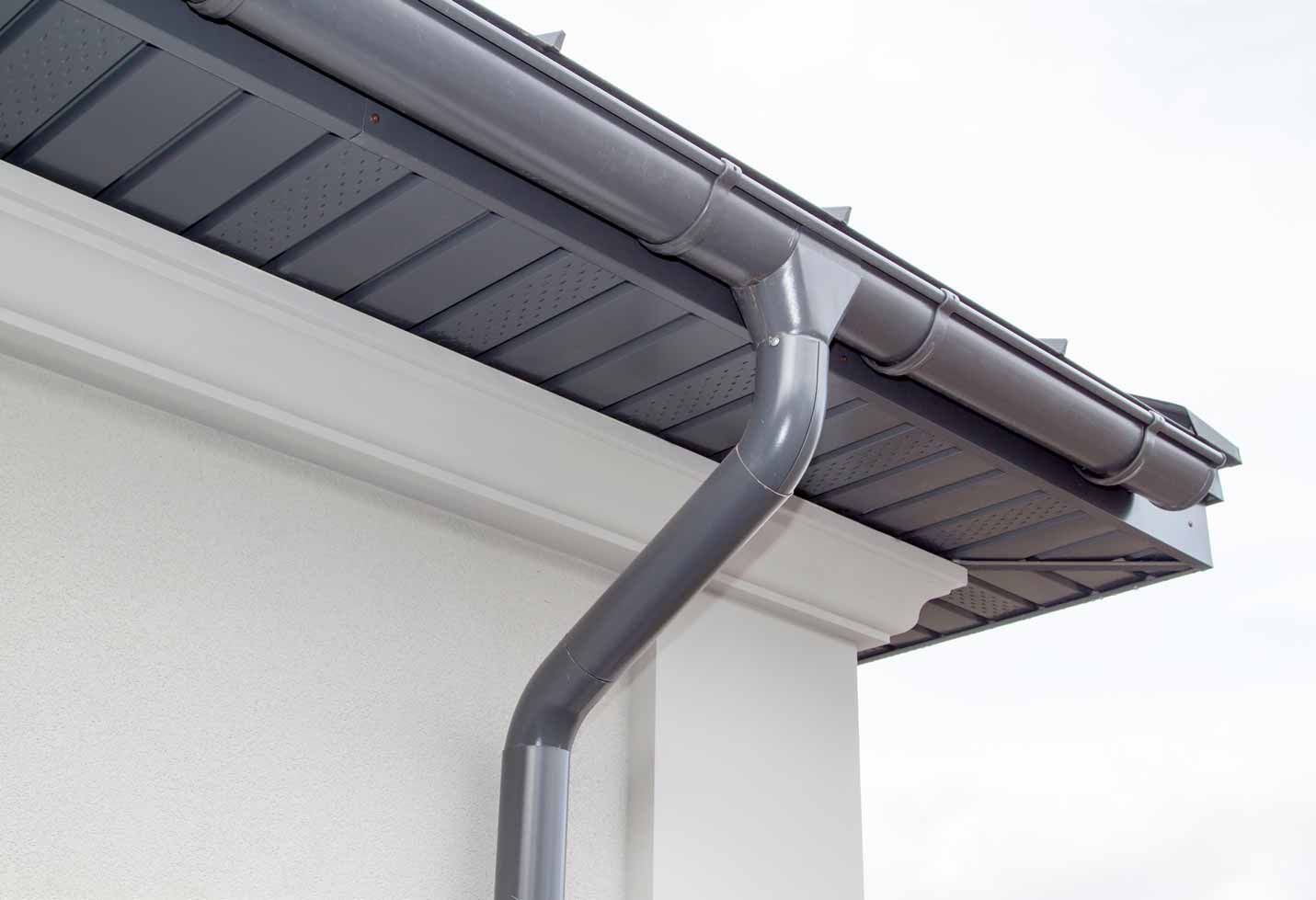 Dark gray gutter and downspout on a white house roofline