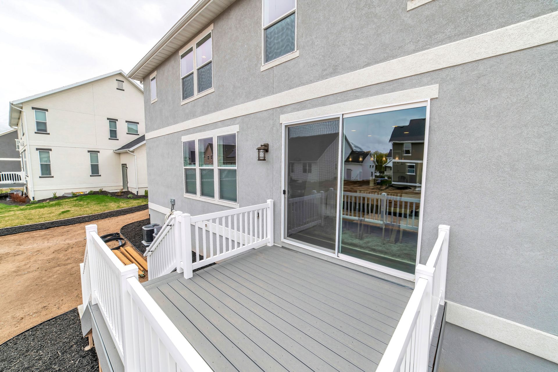 Gray house with a small white-railed front deck and sliding glass door