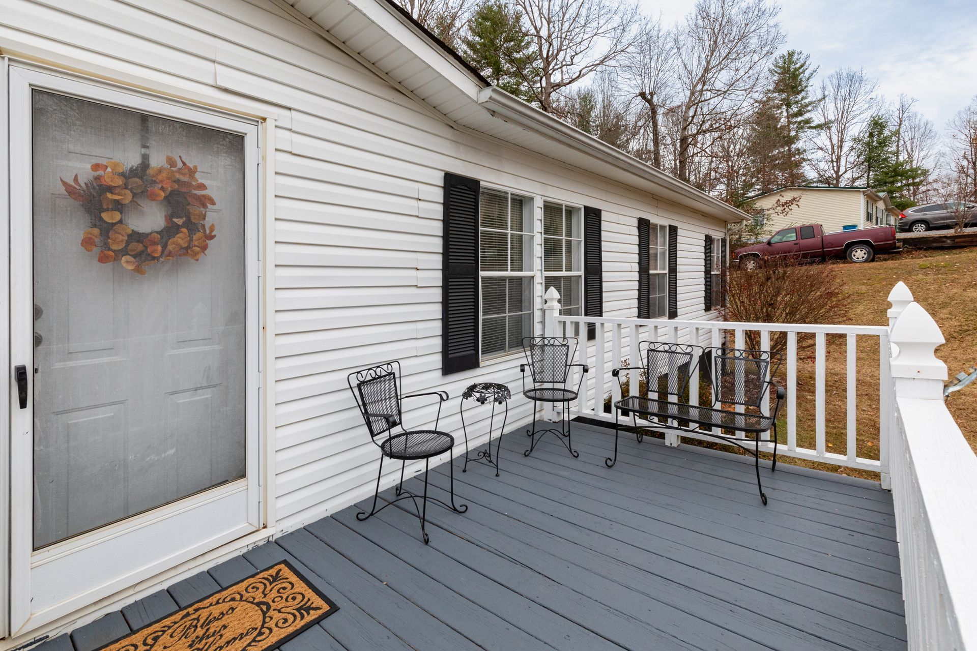 Front porch with gray floor, white siding, black shutters, and a small table and chairs