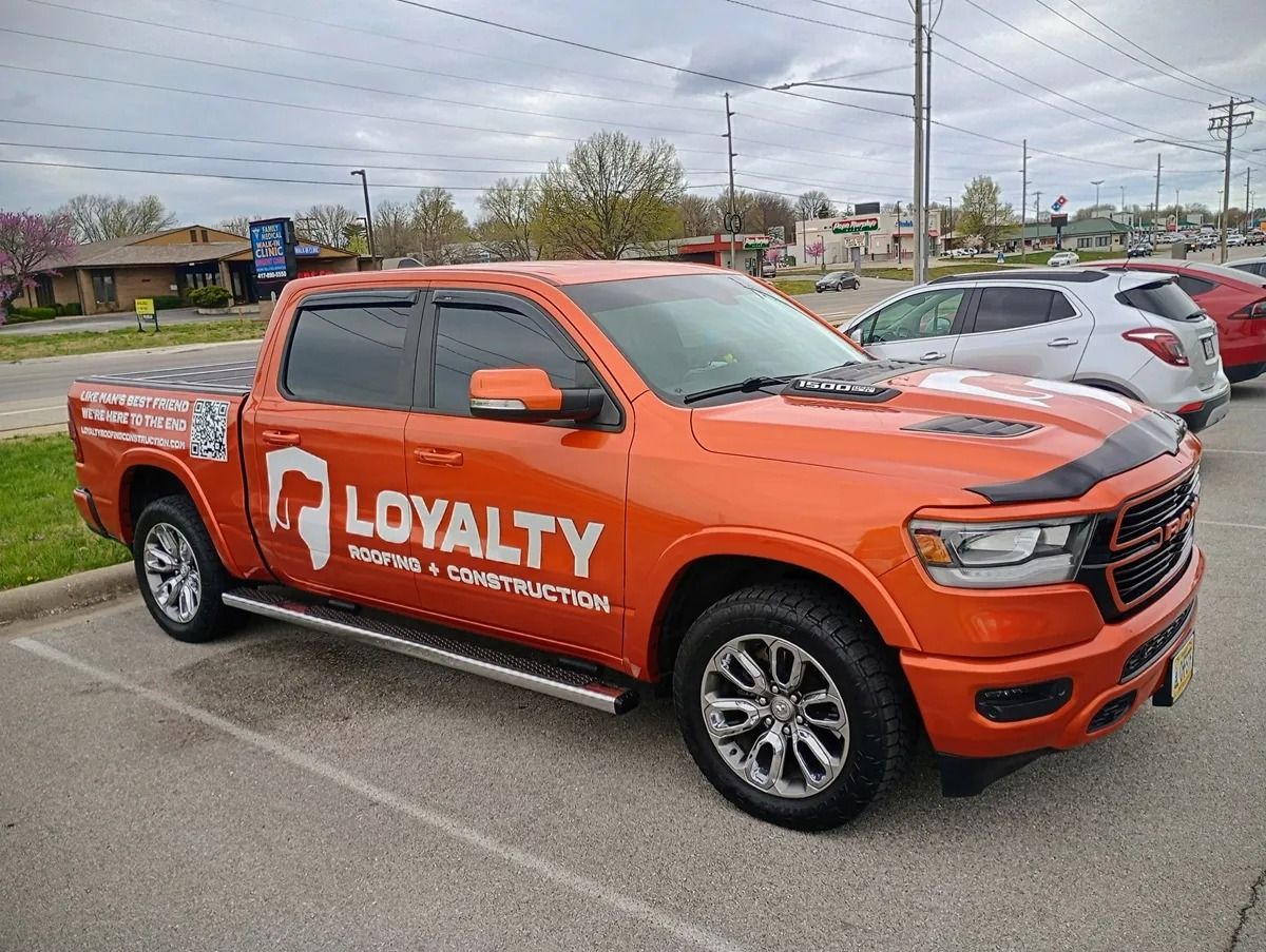 Orange LOYALTY service pickup truck parked in a lot, side view with company logo.