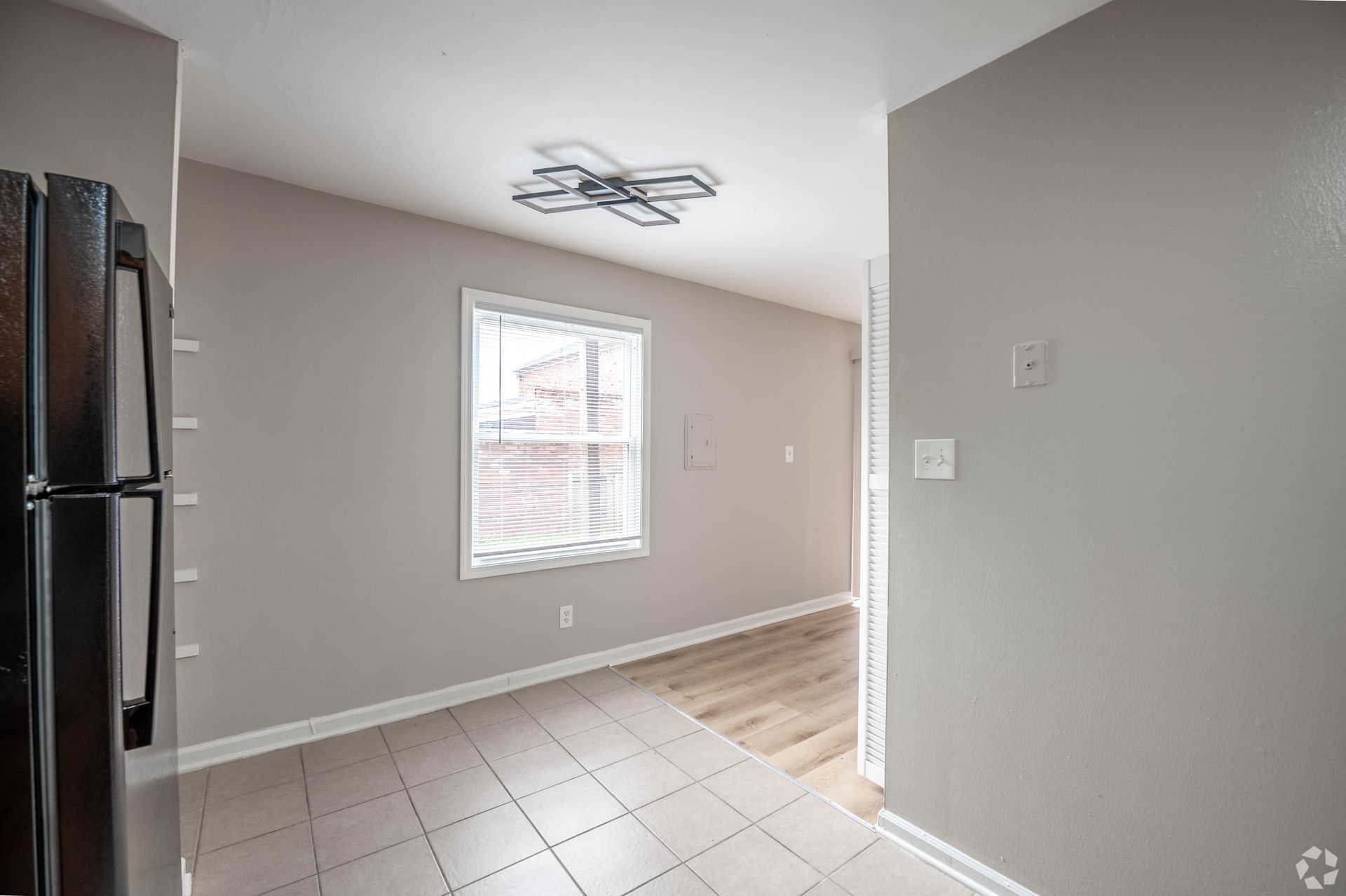 A room with a window, gray walls, and a stainless steel refrigerator.
