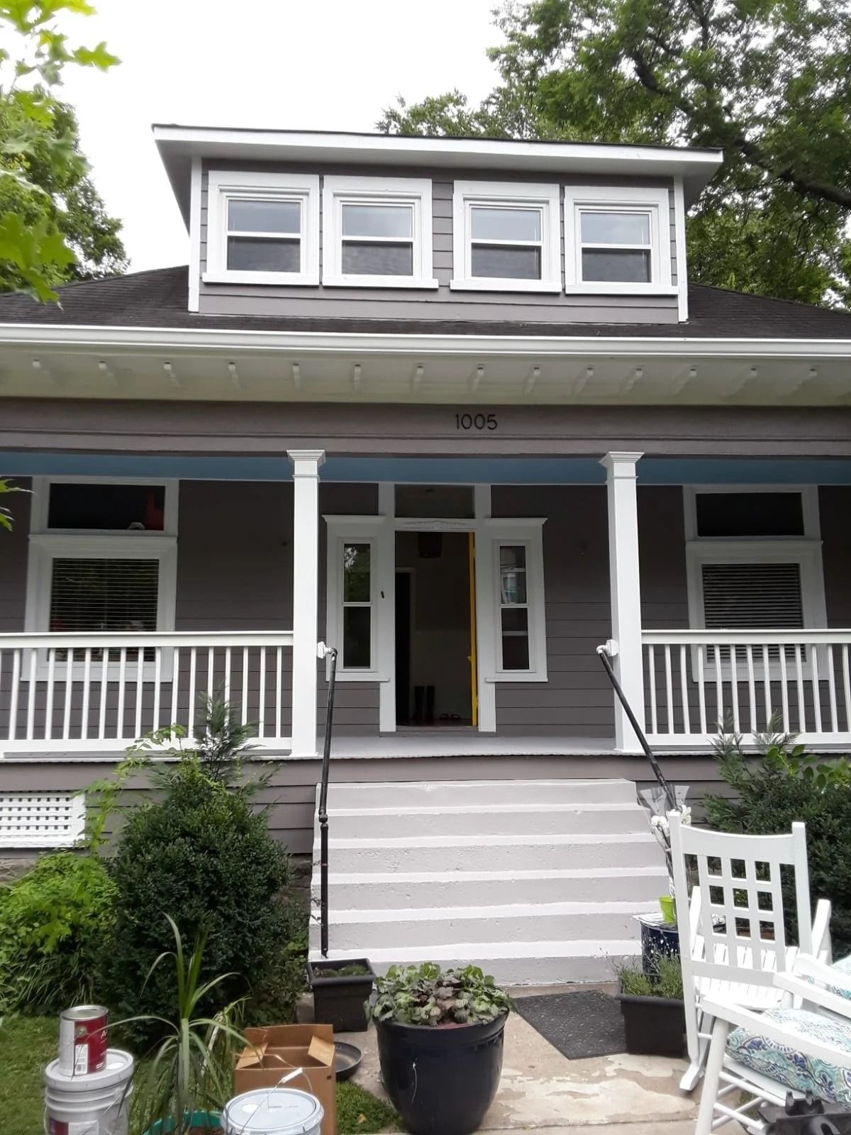 Gray house with porch, white trim, front door open, steps lead up.