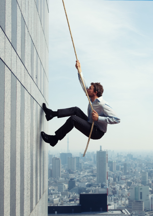 Person rappelling down a skyscraper wall above a city skyline