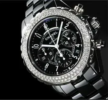 Close-up of a black Chanel chronograph watch with a diamond-studded bezel and silver metal bracelet.