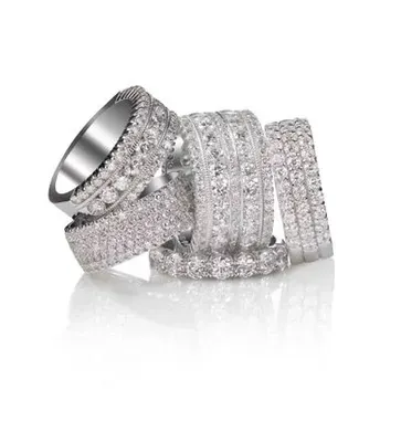 Several sparkling silver crystal-studded rings stacked on a white background