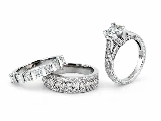 Three silver diamond rings on a white background, including two bands and one engagement ring