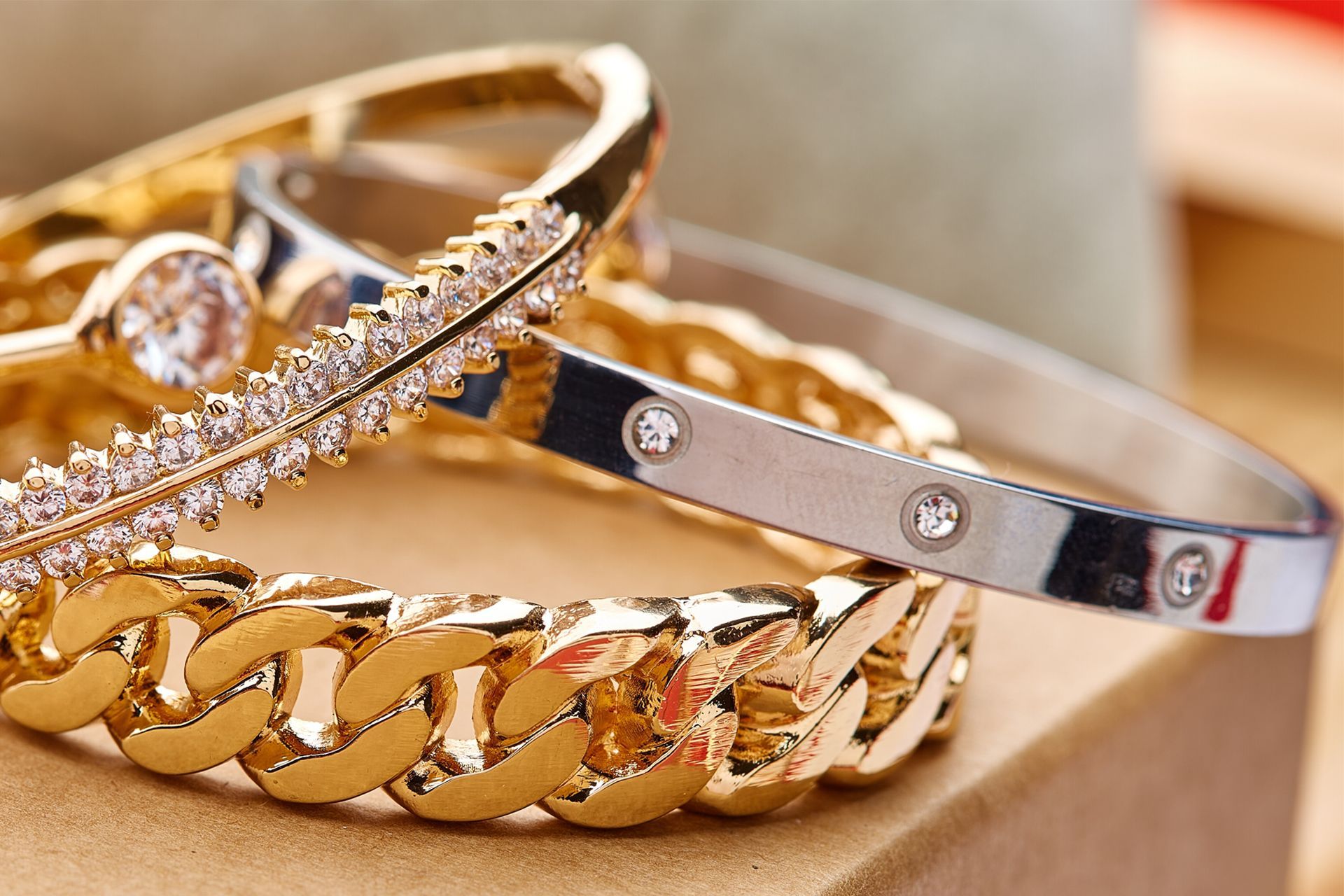 Gold and silver bracelets with gemstones stacked on a soft beige surface