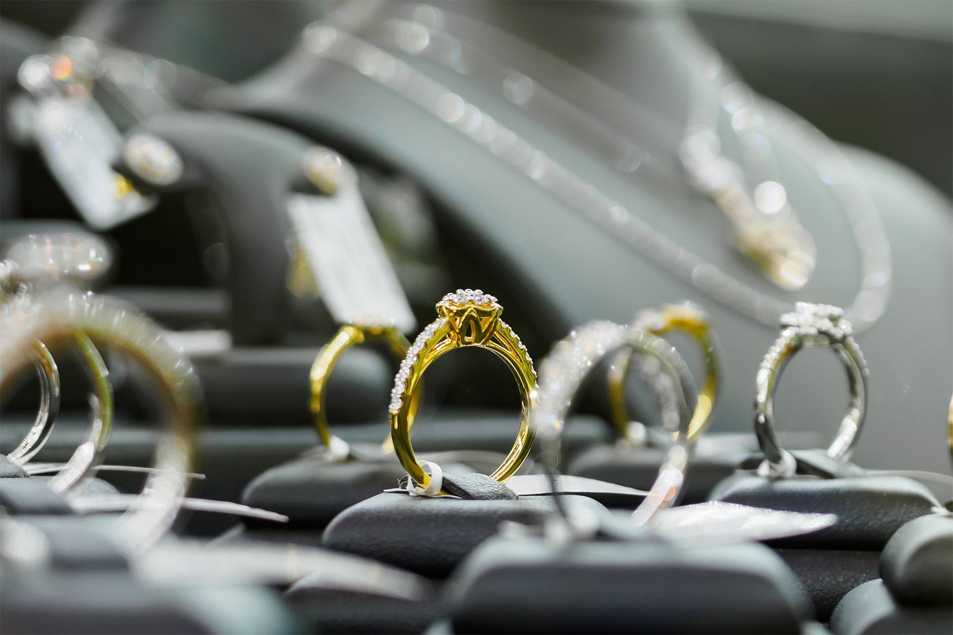 Close-up of several rings displayed on black stands, including a gold ring with a textured setting