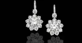 Pair of sparkling floral diamond drop earrings on a black background.