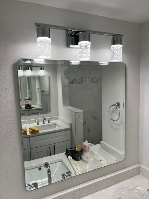 Bathroom mirror with a chrome light fixture above. Reflections show a sink and vanity.