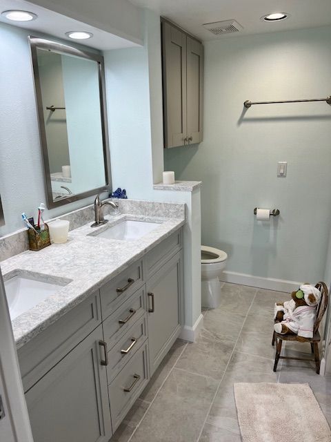 Bathroom with patterned wallpaper, granite countertop, and mosaic tile backsplash.