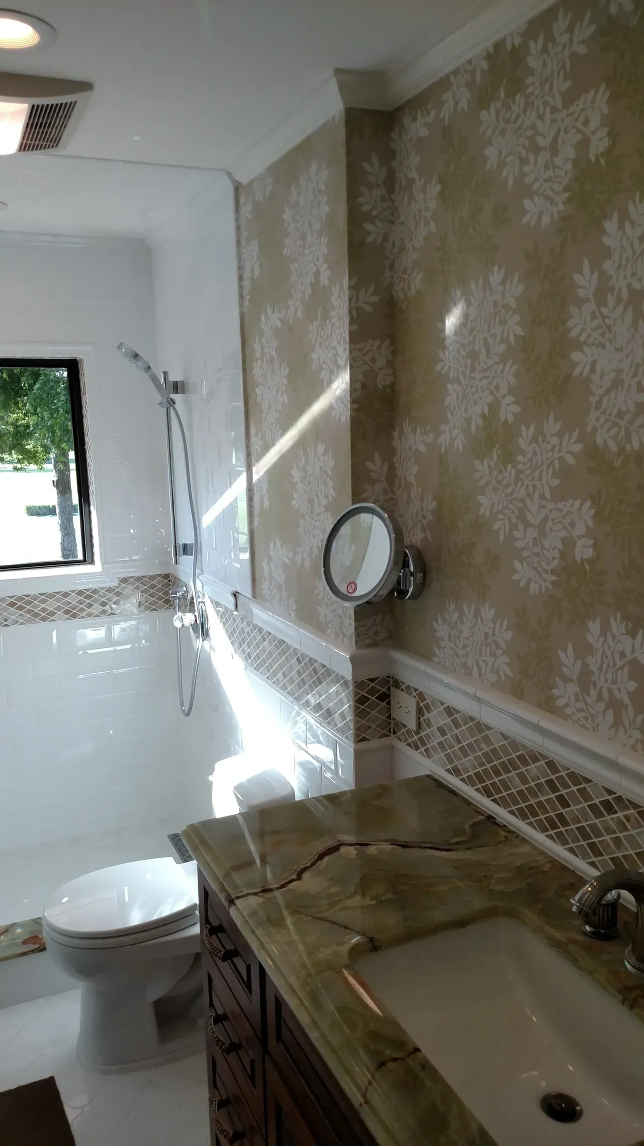 Bathroom with patterned wallpaper, granite countertop, and mosaic tile backsplash.