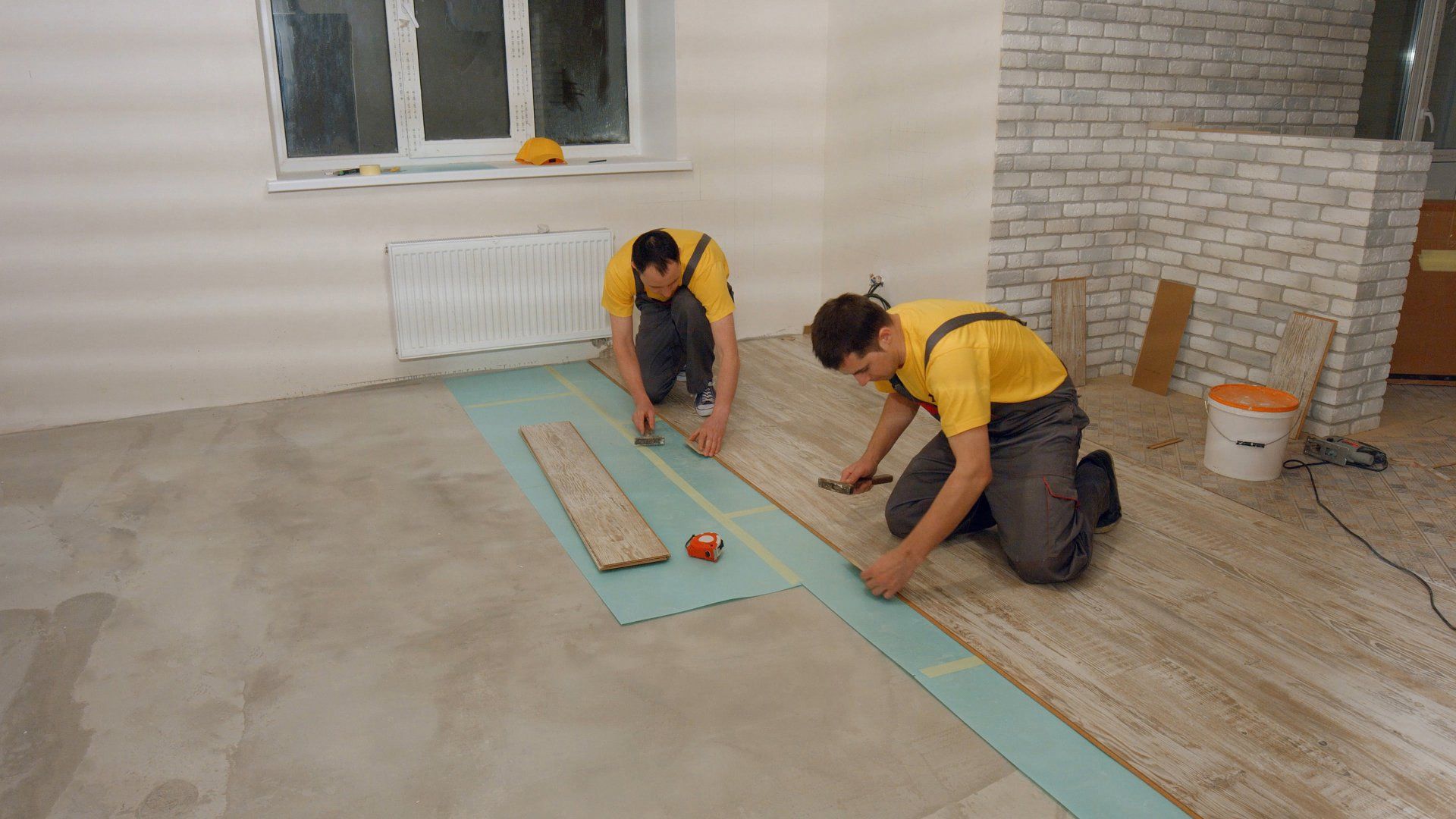 Builders carefully laying wooden flooring 