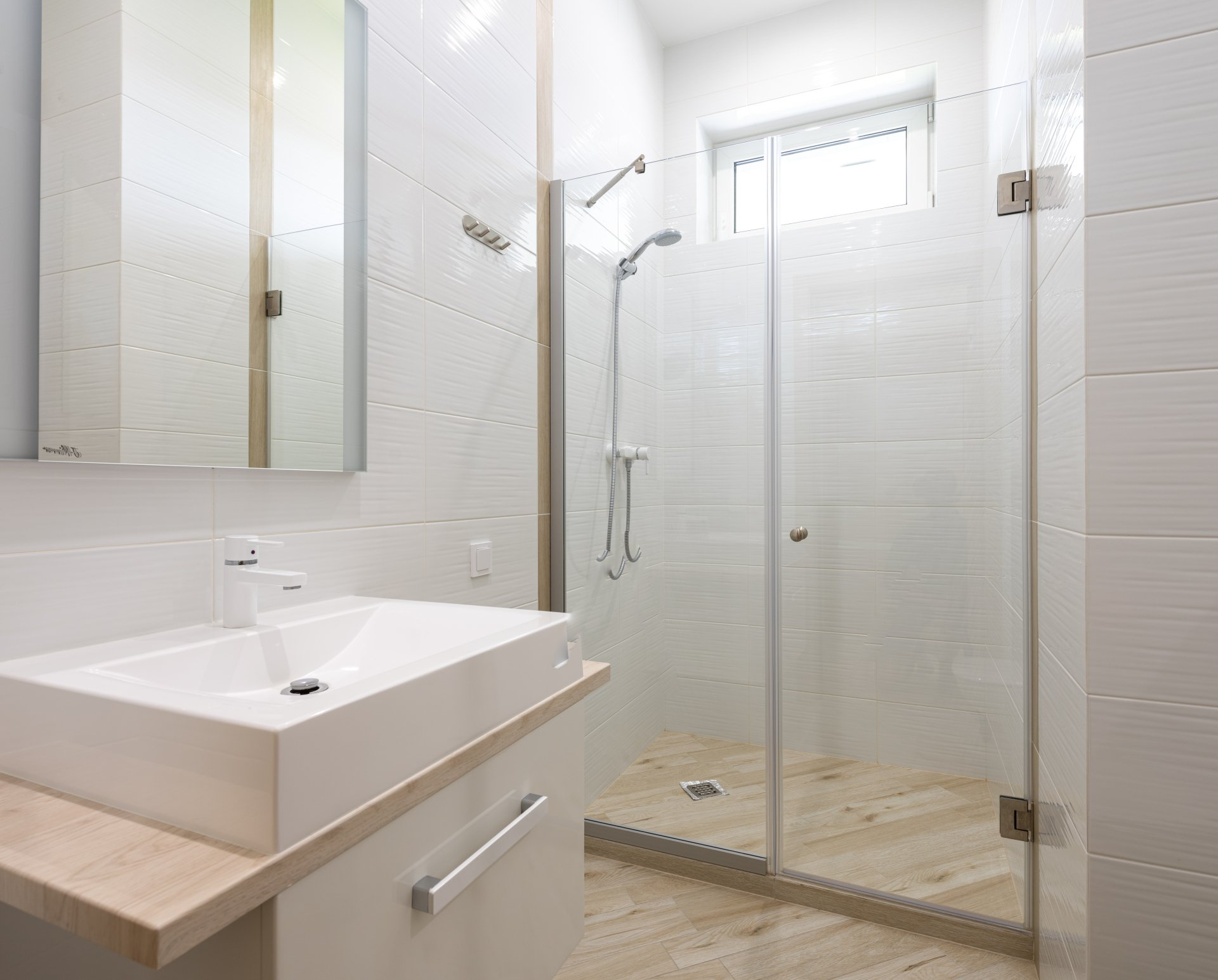Sink, mirror above, and glass enclosed shower.  New fixtures complete this reno