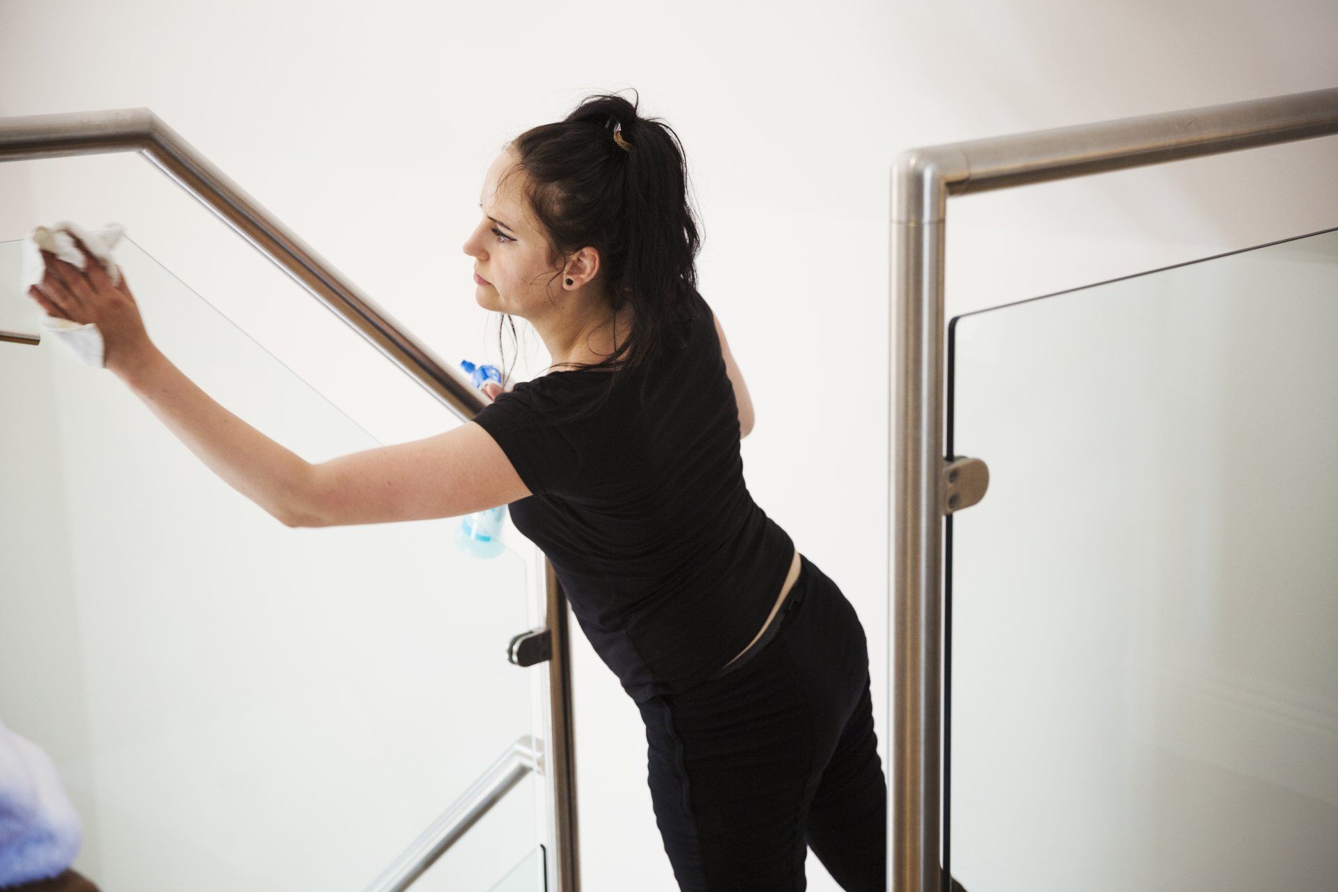 A woman is working on the glass railing of the staircase