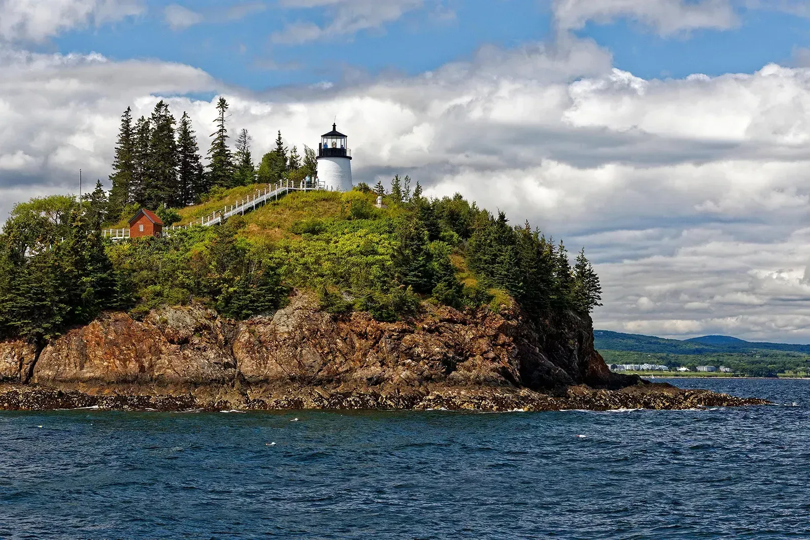 A lighthouse on top of a small island in the middle of the ocean.