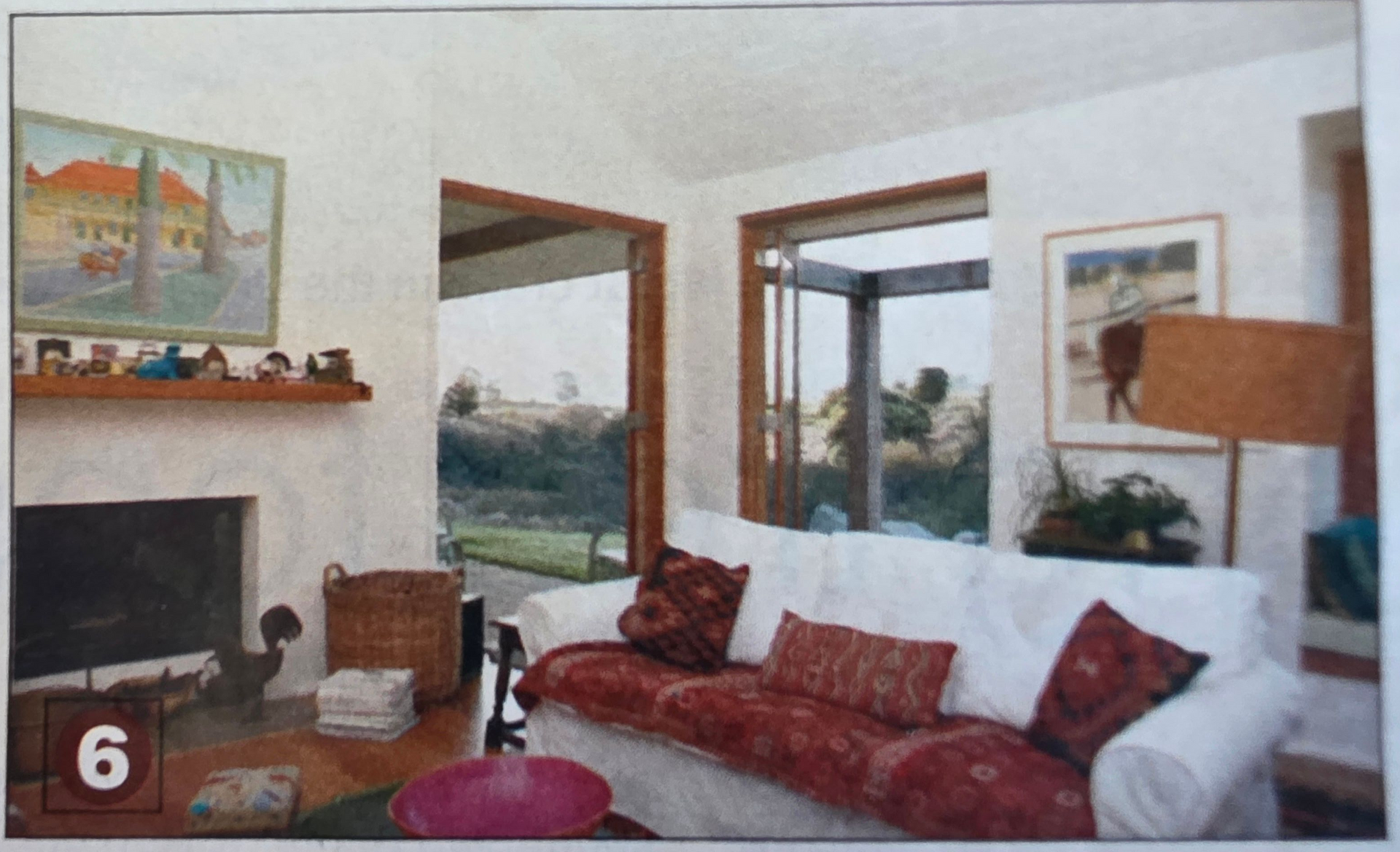 Living room with white sofa, fireplace, artwork, and large windows with outdoor view.