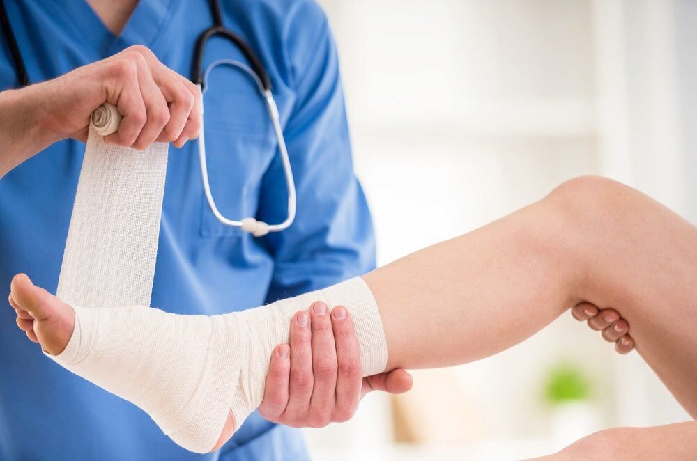 A Doctor Is Wrapping A Patient's Leg With A Bandage — Lake Macquarie Podiatry in Belmont, NSW