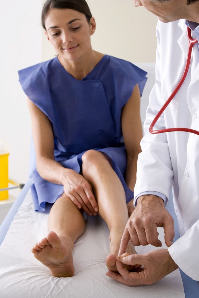 A Doctor Is Examining A Patient's Leg With A Stethoscope — Lake Macquarie Podiatry in Belmont, NSW