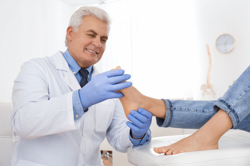 A Doctor Is Examining A Patient's Foot In A Hospital — Lake Macquarie Podiatry in Belmont, NSW