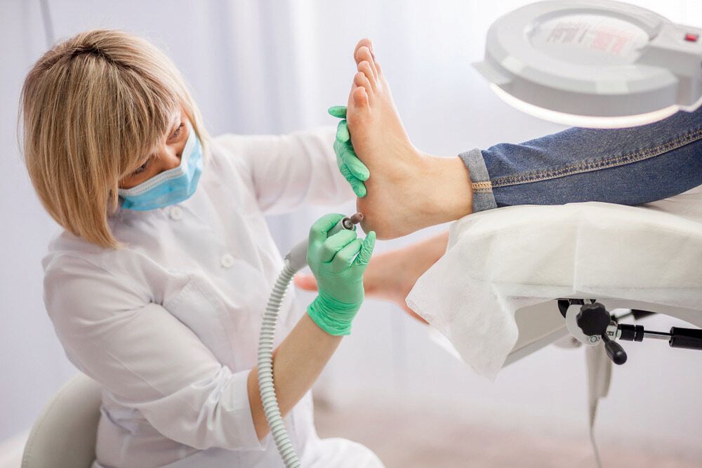 A Woman Is Giving A Foot Treatment To A Patient — Lake Macquarie Podiatry in Belmont, NSW