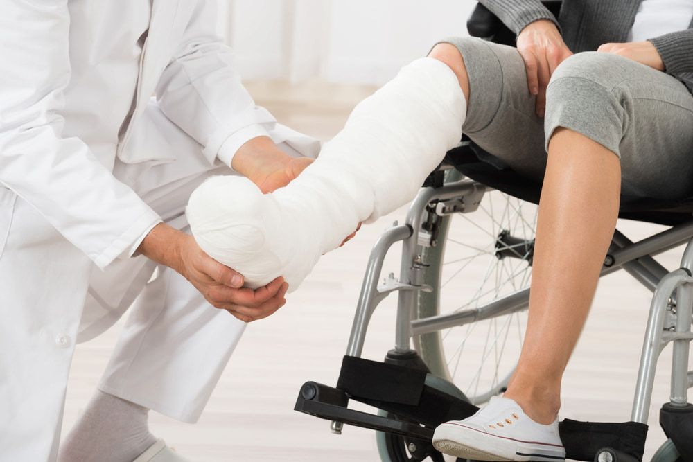 A Woman In A Wheelchair Is Getting Her Leg Cast Removed By A Doctor — Lake Macquarie Podiatry in Swansea, NSW