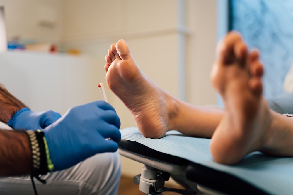 A Doctor Is Examining A Patient's Foot With A Syringe — Lake Macquarie Podiatry in Belmont, NSW