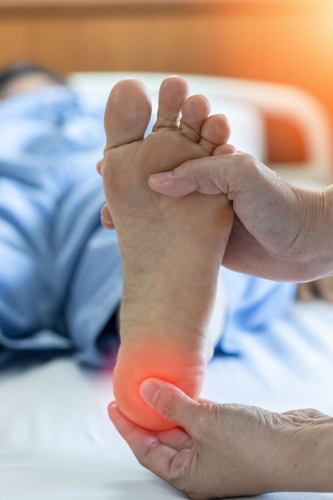 A Person Is Holding A Person's Foot In Pain — Lake Macquarie Podiatry in Belmont, NSW
